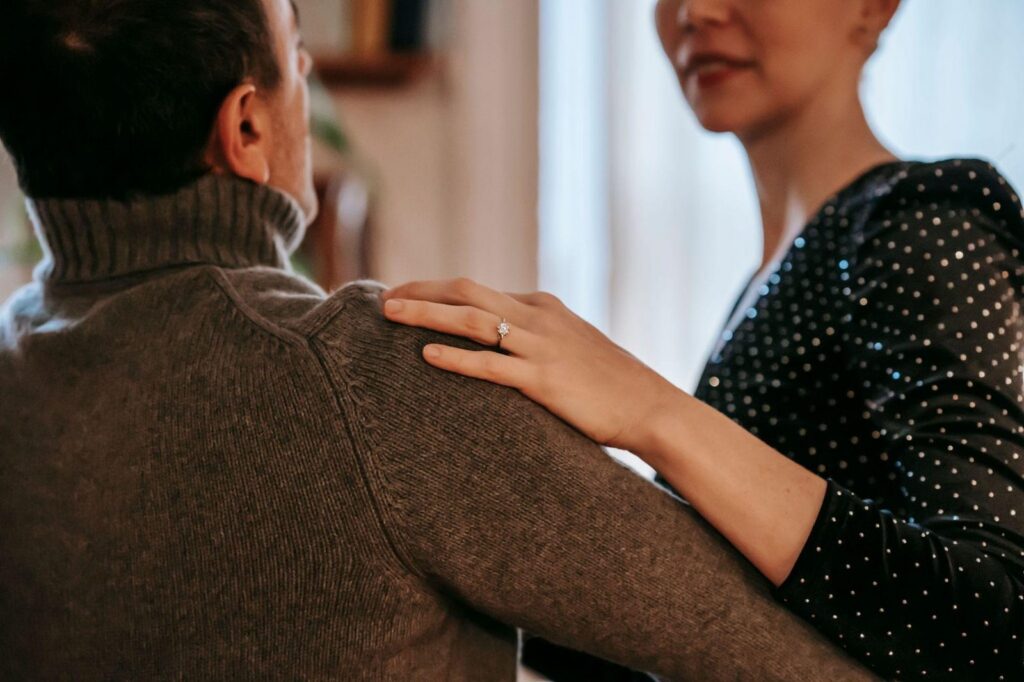 Mujer con anillo de compromiso apoyando la mano en el hombro de su pareja